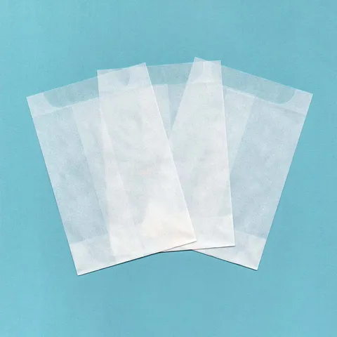 Three plain white glassine bags fanned out on a blue background